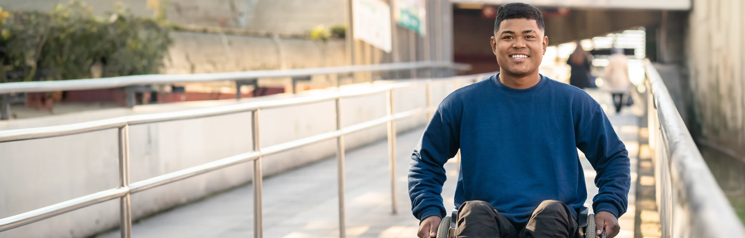 Foto van een lachende, buitenlandse jongen in een rolstoel